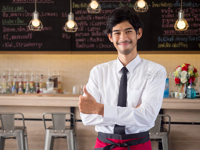 年轻的阿拉伯商人/老板/咖啡师面带微笑站在餐饮餐厅/咖啡馆/商店前